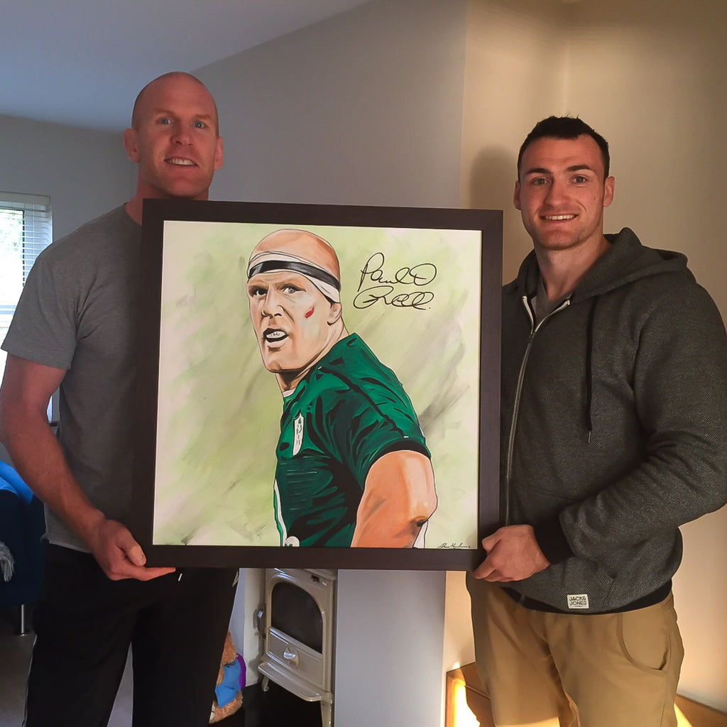 Paul O'Connell and Shane Monahan holding a painting of Paul O'Connell